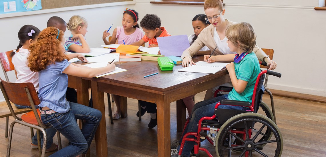 pretty-teacher-helping-pupils-in-classroom